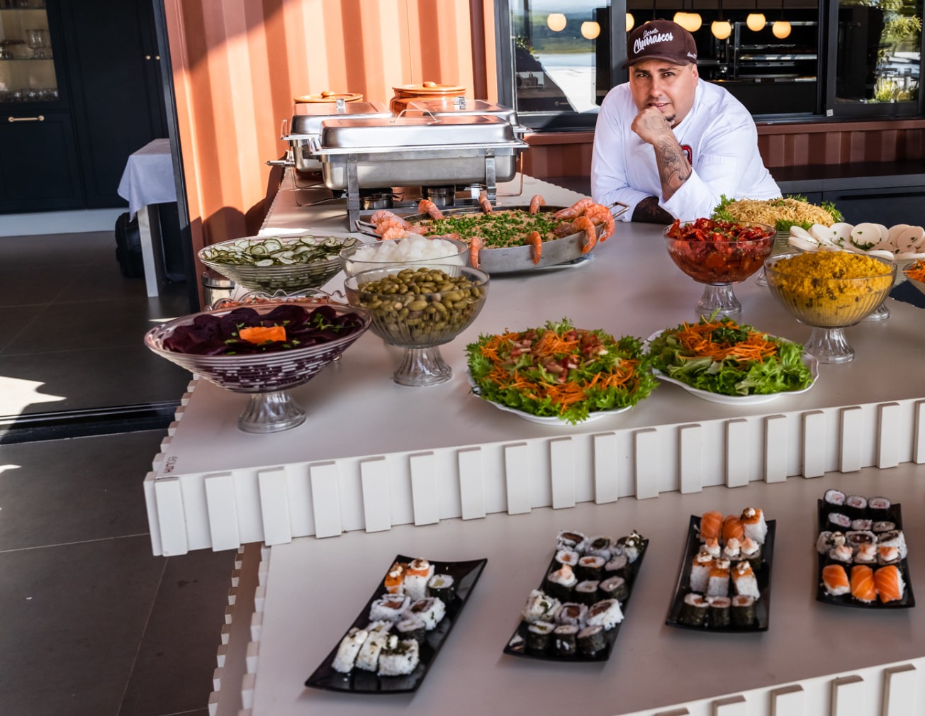 Chef da Conecta Buffet atrás do balcão com os pratos do buffet